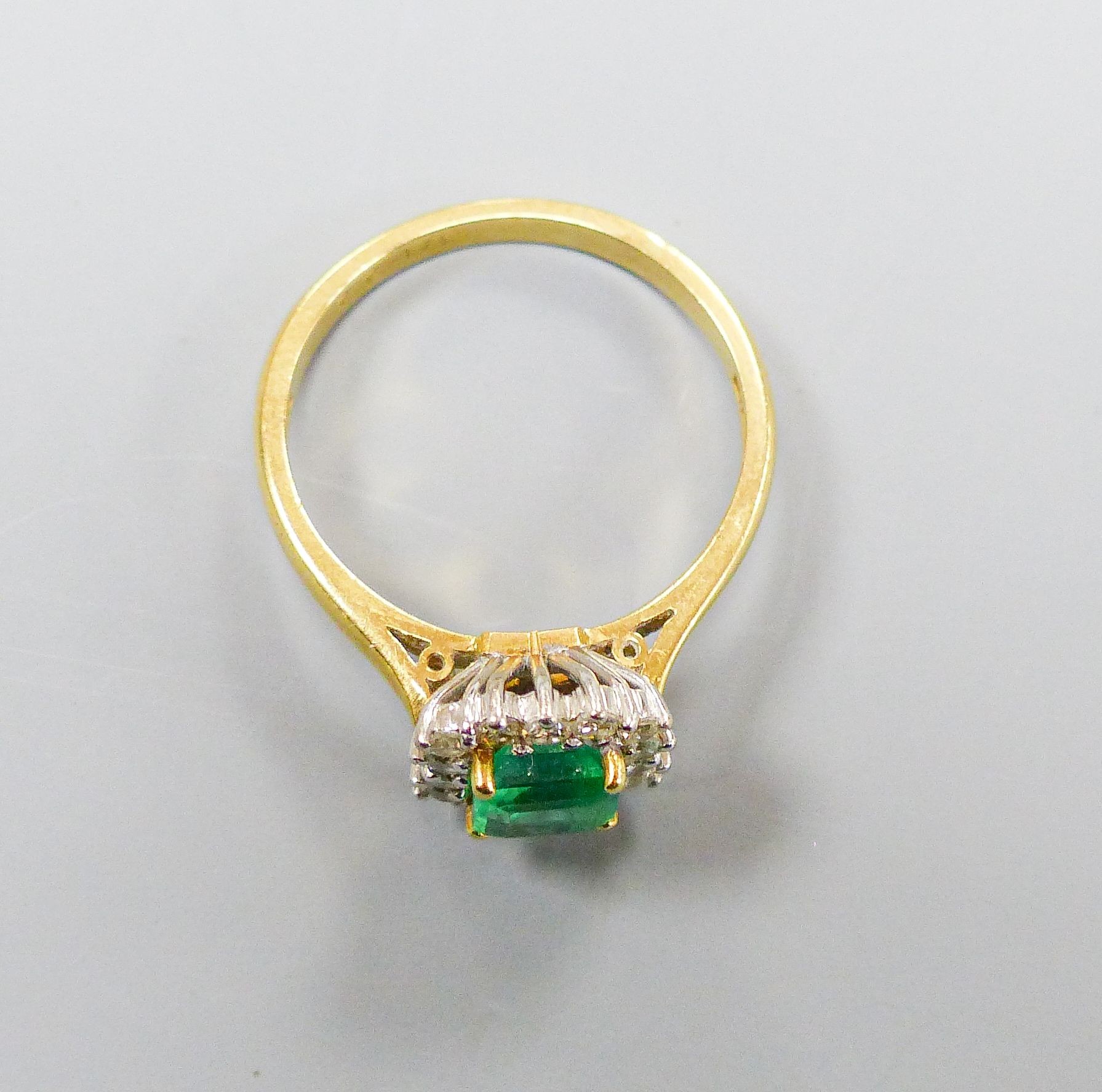 A modern 18ct gold, emerald and diamond set square cluster ring, size O, gross weight 4.3 grams.